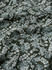 A close-up of a dark olive green fabric with a light blue and white floral block print pattern.
