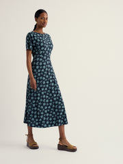 Woman wearing a blue floral dress on a white background.