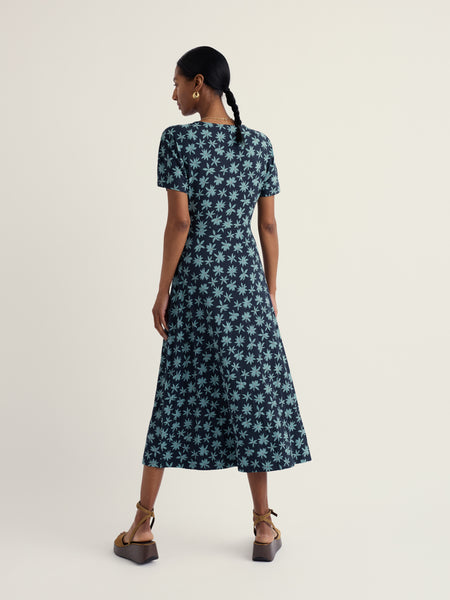 Woman wearing a blue floral dress on a white background.