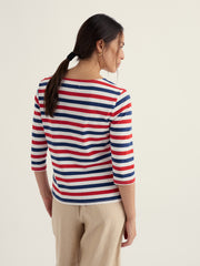 Woman wearing a red, white, and blue striped shirt on a beige background.