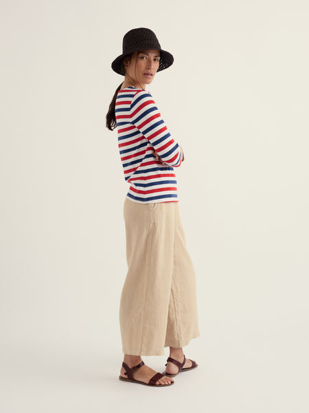 Woman wearing a striped sweater and wide-leg pants on a white background.
