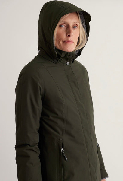 A woman wearing an olive green hooded jacket, shown from the chest up against a plain light gray studio background.